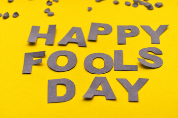 Paper letters made of gray paper are lined with a fool's day on a yellow background close-up. High quality photo