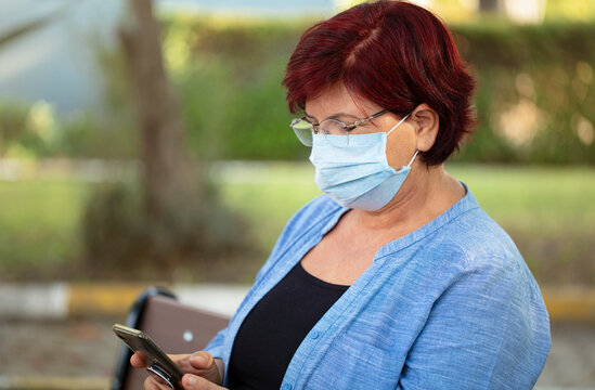 health, safety and epidemic concept. Mature woman wearing protective medical mask for antivirus sitting on bench in summer park.
