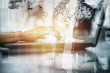 Close-up on the hands of a woman typing on a laptop keyboard. Double exposure effects