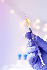 doctor, medic holds in hand a thin syringe for intramuscular injection on a technological blue background, prepares to do vaccination, concept of studying COVID-19 virus