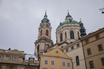 Lesser Town Square, view of Baroque Church of Saint Nicholas, large dome and tower, town with historical buildings, snow, winter day, Mala Strana district, Prague, Czech Republic