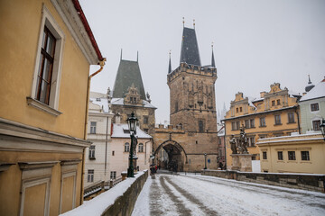 Charles Bridge landmark looking towards Lesser Town with bridge tower, Baroque Church of Saint Nicholas and Prague Castle in background, snow in winter day, Prague, Czech Republic,