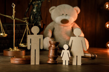Wooden figures of family with teddy bear and gavel on a table. Divorce and alimony concept.