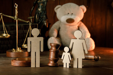 Wooden figures of family with teddy bear and gavel in a courtroom. Divorce and alimony concept.