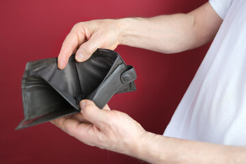 male hand hold empty wallet on red background, counting a bundle of money, concept of cash, payments,