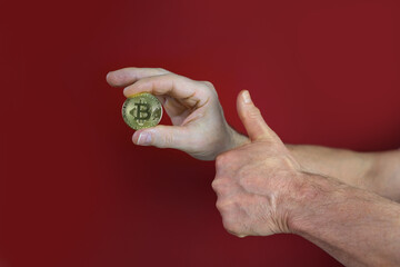 male hand hold coin gold bitcoin on red background, sale charts, up and down concept, banking, saving money, payments, e-business