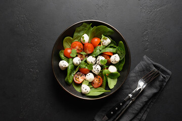 Salad with spinach, cherry tomatoes, basil, onion and Mozzarella. Fresh tasty vegan food. View from above.