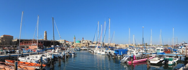 Fototapeta na wymiar Acre, Israel - February 14, 2021. Beautiful panoramic views of the yachts at the pier and ancient architecture in the old city of Acre. Buildings of Muslim and Christian religions in one place. 