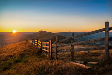 Stunning Mam Tor Peak District early morning dawn sunrise with long fence and beautiful golden hour...