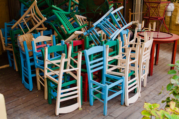 Fototapeta na wymiar Colorful chairs piled from a closed restaurant due to COVID19 in Plaka, Athens.