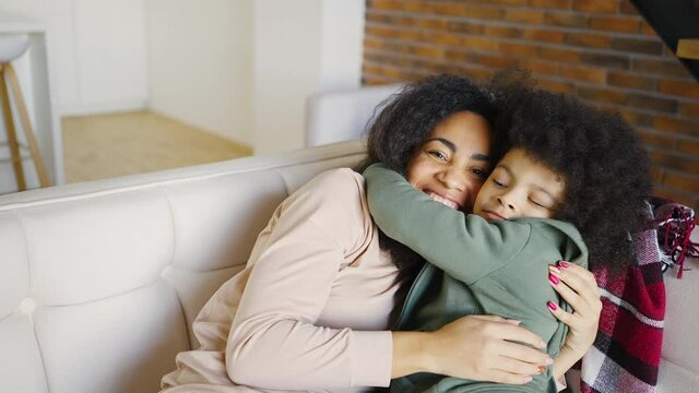 Portrait of happy mother hugging her son. Portrait of a joyful mother and her son in the sofa. Smiling boy hugging his mother expressing tender feelings. Mothers Day