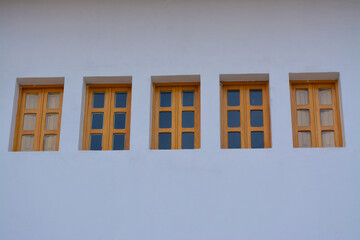 Fachada blanca minimalista con cinco ventanas de madera y cristal