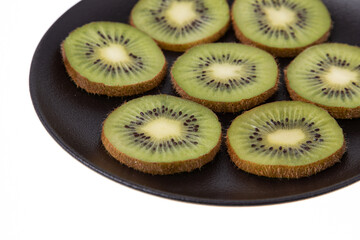 Ripe and green kiwi sliced with seeds visible on black plate