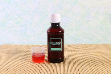 herbal ayurvedic cough syrup or expectorant bottle with measure cup and label isolated for...