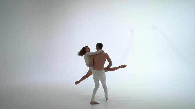 Aerial straps duo wearing white costume on white background doing performance. Concept of romantic couple 
