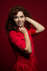 Fototapeta premium close-up portrait of a red-haired woman in a red dress on a red background in the studio