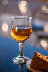A glass of white dessert wine and a carrot pie on the table in a cafe