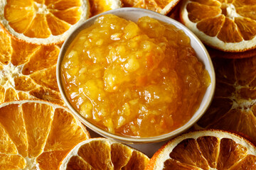Orange marmalade in bowl. Portion of orange fruit jam with dried orange slices.