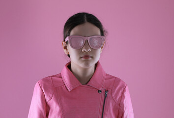 portrait of a teenage girl in a pink leather jacket on a pink background