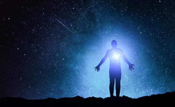 Silhouette of man stand and see in the night sky with stars. Galaxy and space. Light from the chest. Astrology sign. Esoterica and psychology. Elements of this image furnished by NASA