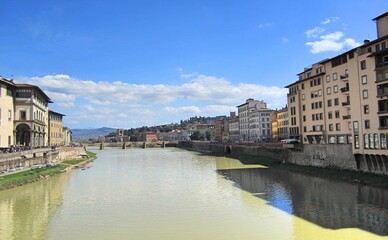 Obraz premium View of the Arno River in Florence, Italy. Yellow water. A bridge in the distance, buildings on the sides 