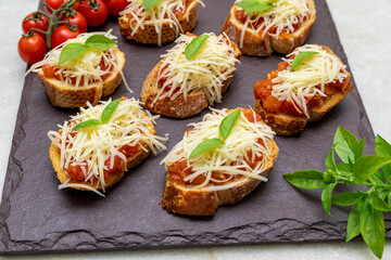 Bruschetta with tomato, basil and parmesan cheese on wooden board. Traditional Italian appetizer or snack, antipasto