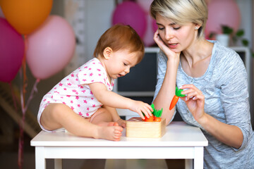 babe enthusiastically adds carrots to the game as a child, the mother quietly helps. side view