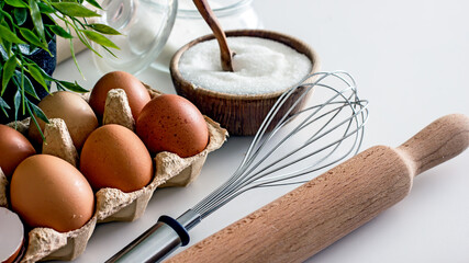 Ingredients and accessories for baking meringue. Brown eggs, sugar, whisk on the kitchen table...