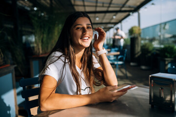 Young woman in a cafe holding a smartphone in her hands