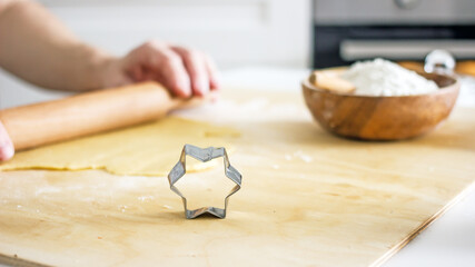 The process of making homemade asterisk shortbread cookies. Male hands cut cookies using a mold made of rolled dough. Authentic home hobby