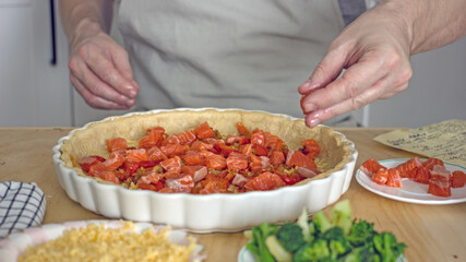 A man in the kitchen bakes a fish pie quiche close-up