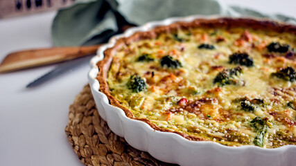 Homemade French quiche pie with salmon and broccoli in a baking dish close-up