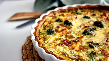 Homemade French quiche pie with salmon and broccoli in a baking dish close-up