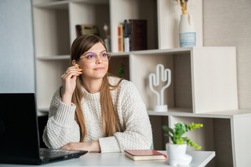 Fototapeta na wymiar Head shot happy young female manager wearing wireless headphones, looking at laptop screen, holding pleasant conversation with partners clients online, working remotely at workplace.