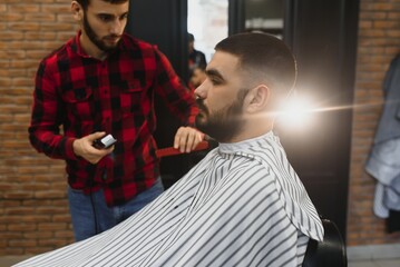 Serious Young Bearded Man Getting Haircut By Barber. Barbershop Theme