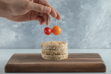 Female hand taking tomatoes from stack of crispbread