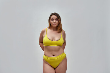 Attractive curvy young female model wearing yellow underwear looking at camera while posing...