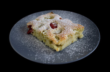 Appetizing piece of cake on a grey plate on black background close-up