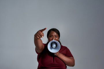 Confident plus size african american woman in casual clothes pointing at camera, holding a...