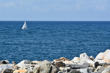Fototapeta na wymiar Una barca a vela naviga sul mare blu.