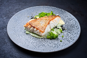 Modern style traditional fried skrei cod fish filet with mashed potatoes and baby broccoli served as close-up on ceramic design plate with copy space