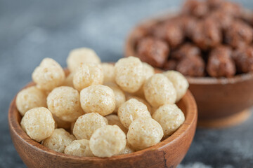 Wooden bowls with sweet corn balls on a gray background