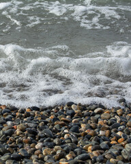 The sea wave has foamed and covers the pebble beach.