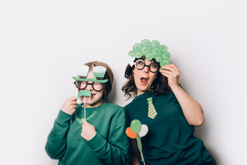 Young girl and woman are preparing for the St Patricks Day party with photo booth props, Ireland traditional holiday, 17 March