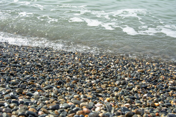 The sea wave covers the pebble beach. Horizontal photo