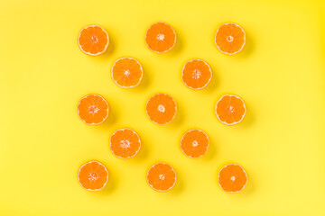 Fruit pattern of fresh mandarin slices on yellow background. Flat lay, top view. Pop art design, creative summer concept. Half of citrus in minimal style. Tangerine.