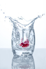 Water splash in a glass with red strawberry in it. 