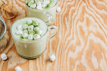 Homemade warm Matcha latte, green tea with coconut milk and marshmallow on wooden background.