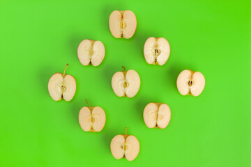 Fototapeta na wymiar Fruit pattern on green background. Apple halves geometrical layout. Flat lay, top view. Food background. . Pop art design, creative summer concept.