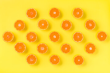 Fruit pattern of fresh mandarin slices on yellow background. Flat lay, top view. Pop art design, creative summer concept. Half of citrus in minimal style. Tangerine.